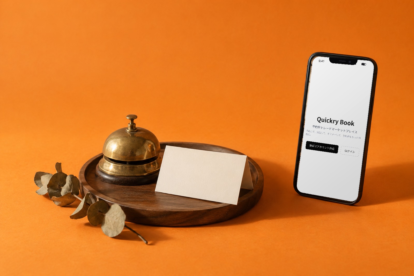 Quickry Bookの画面を表示したスマートフォンと、受付の呼び鈴